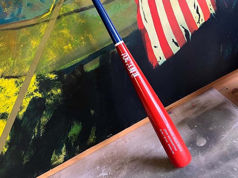 Red, white, and blue Razorbill bat displayed against an American flag background, celebrating patriotic spirit with bold colors and custom design.